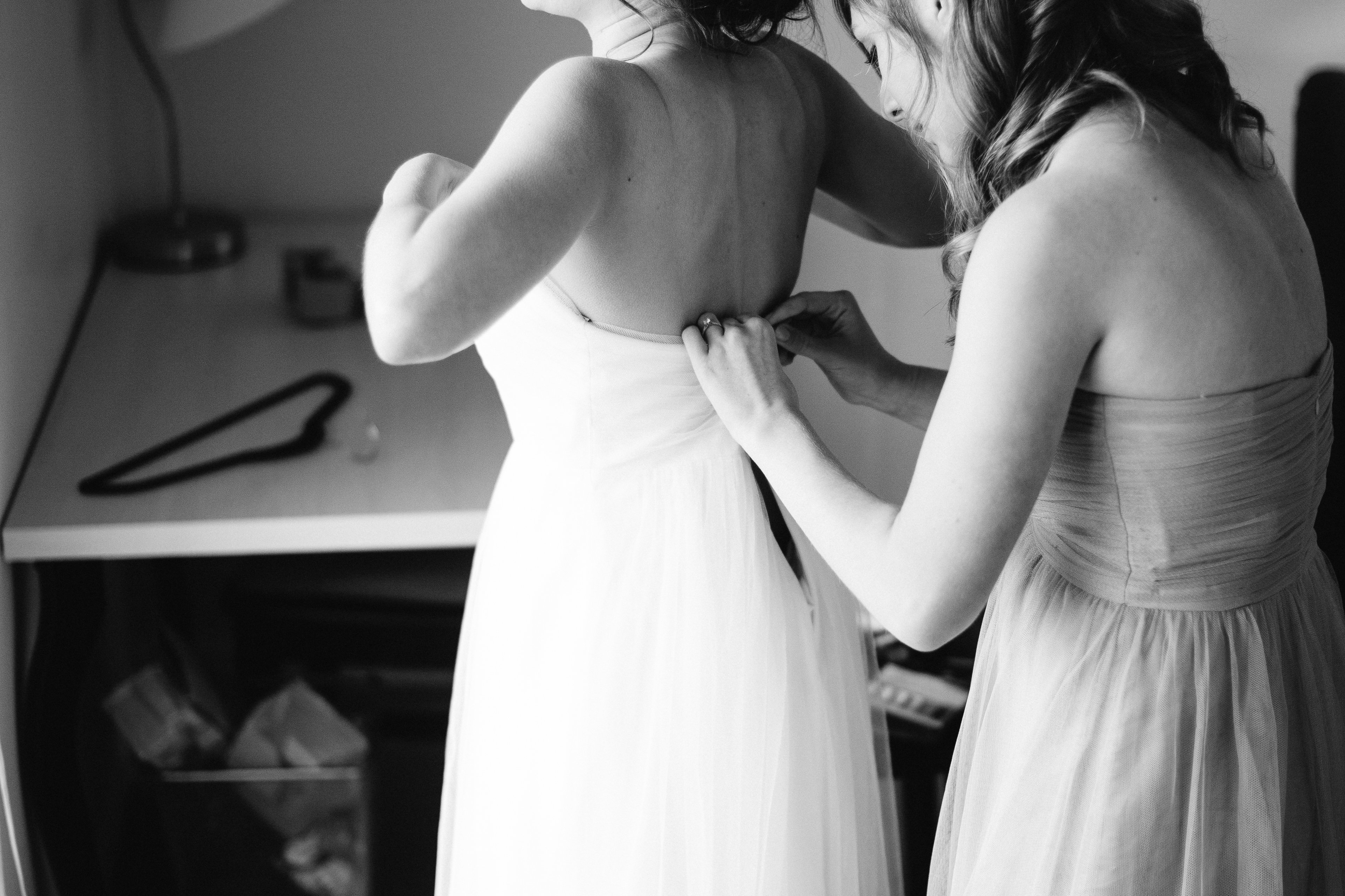 bride getting help while putting dress on