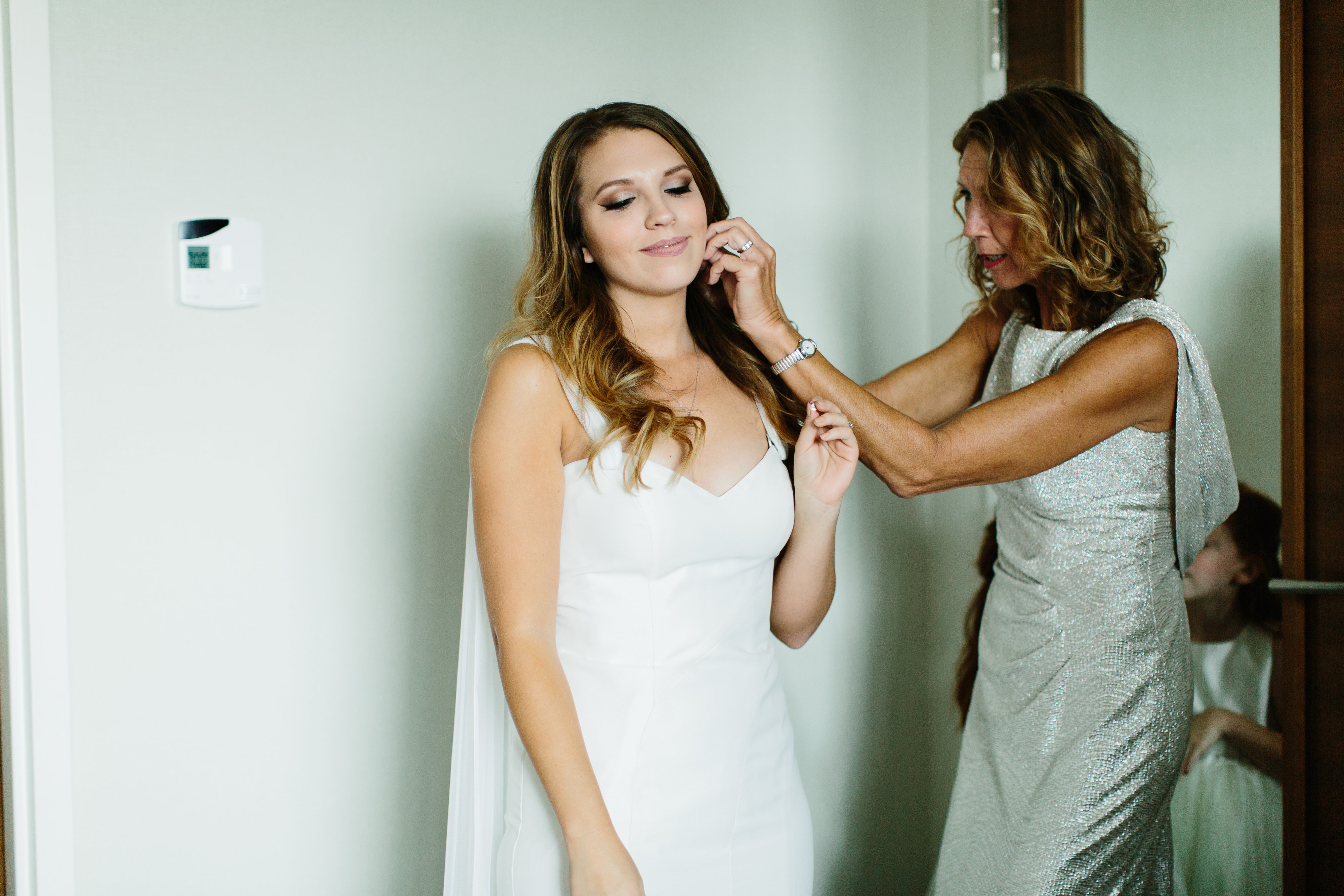 mother of bride putting earrings on bride