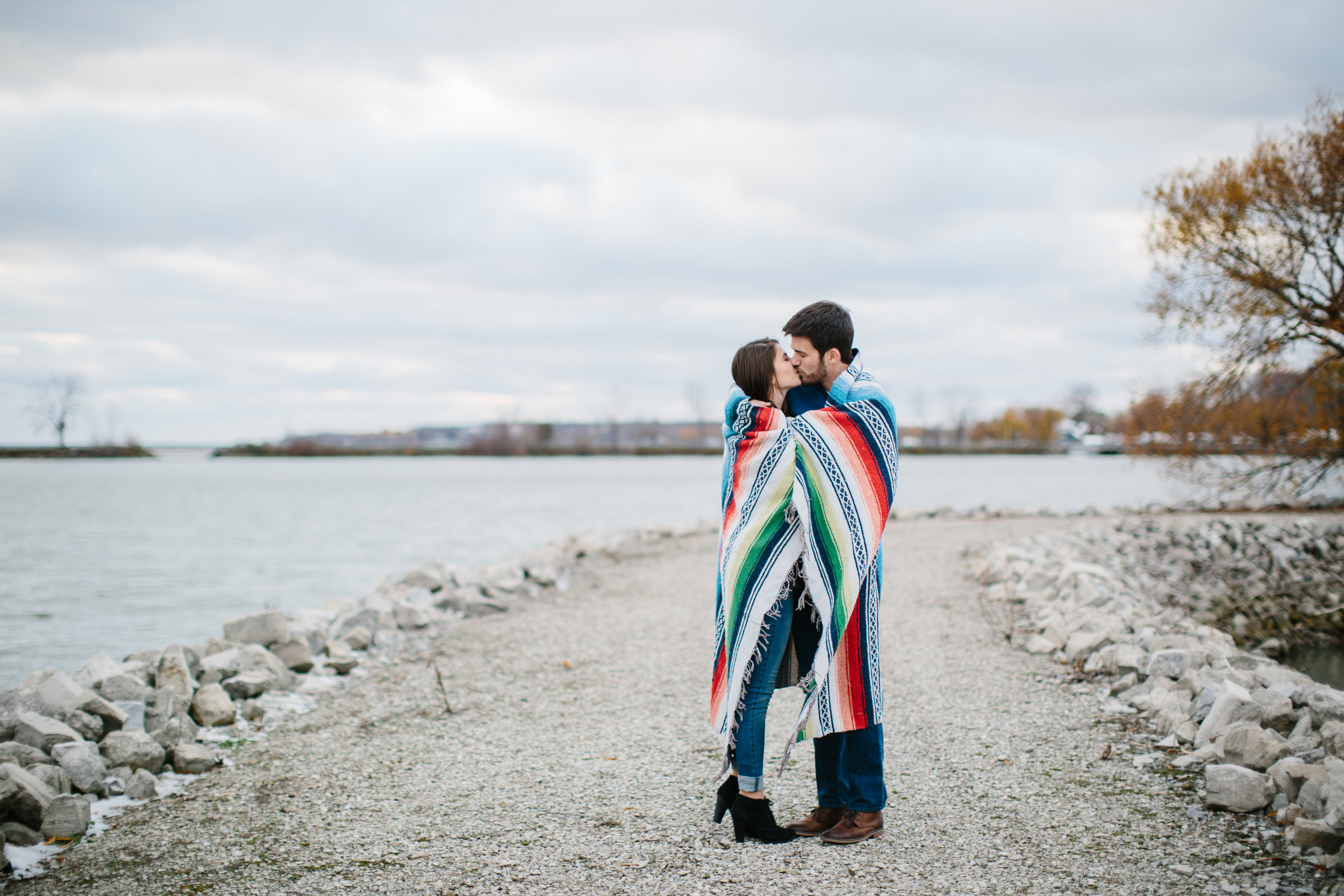 couple kissing in blanket by lake