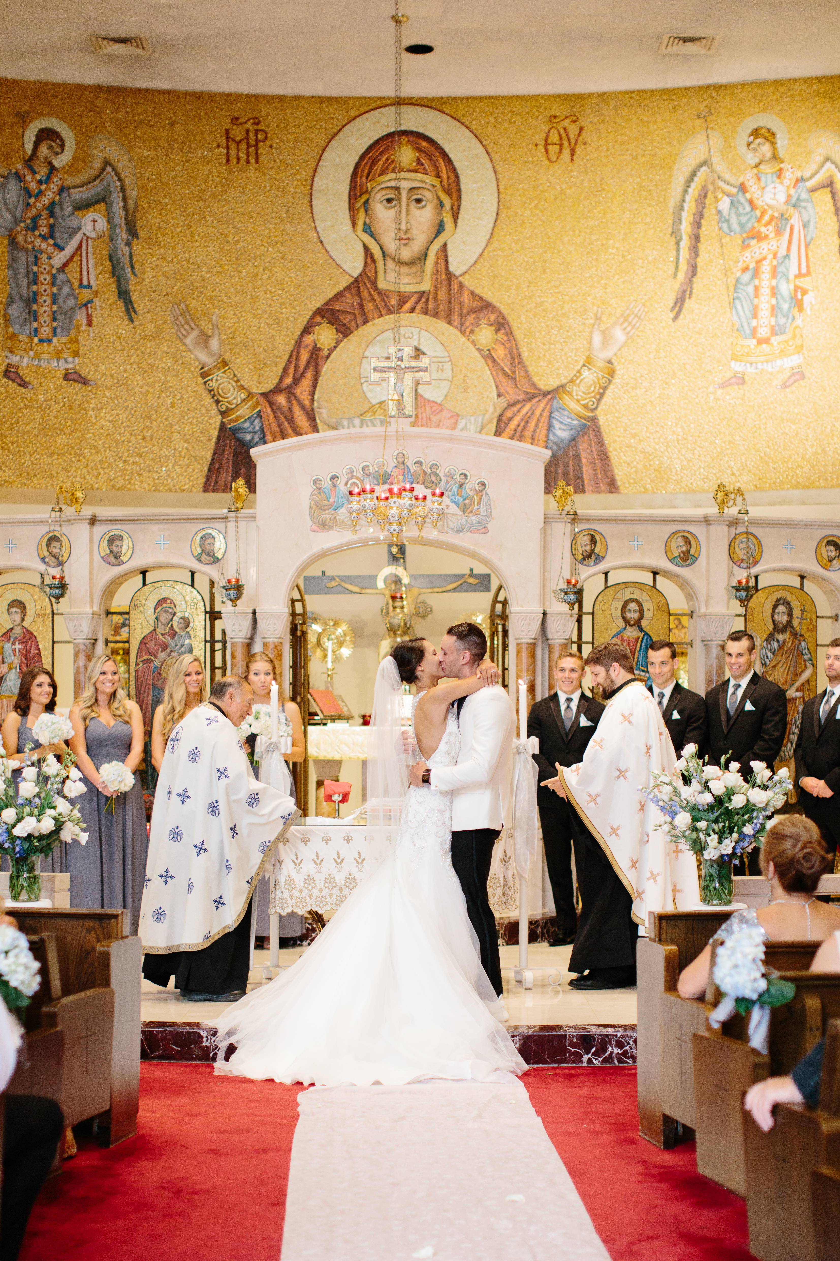 Couple kiss during their Greek Orthodox Wedding