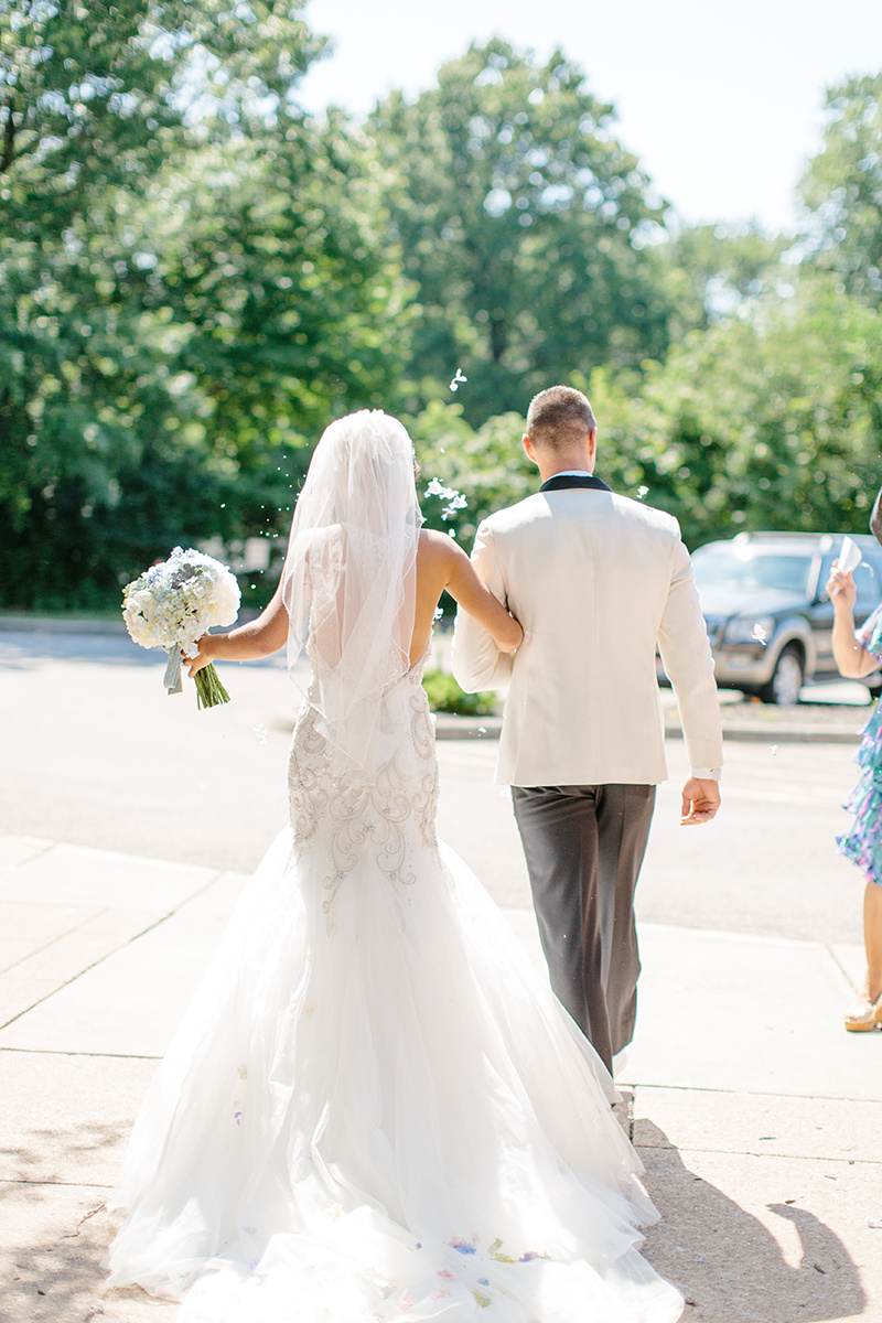 Bride and groom run through flower petals at wedding 