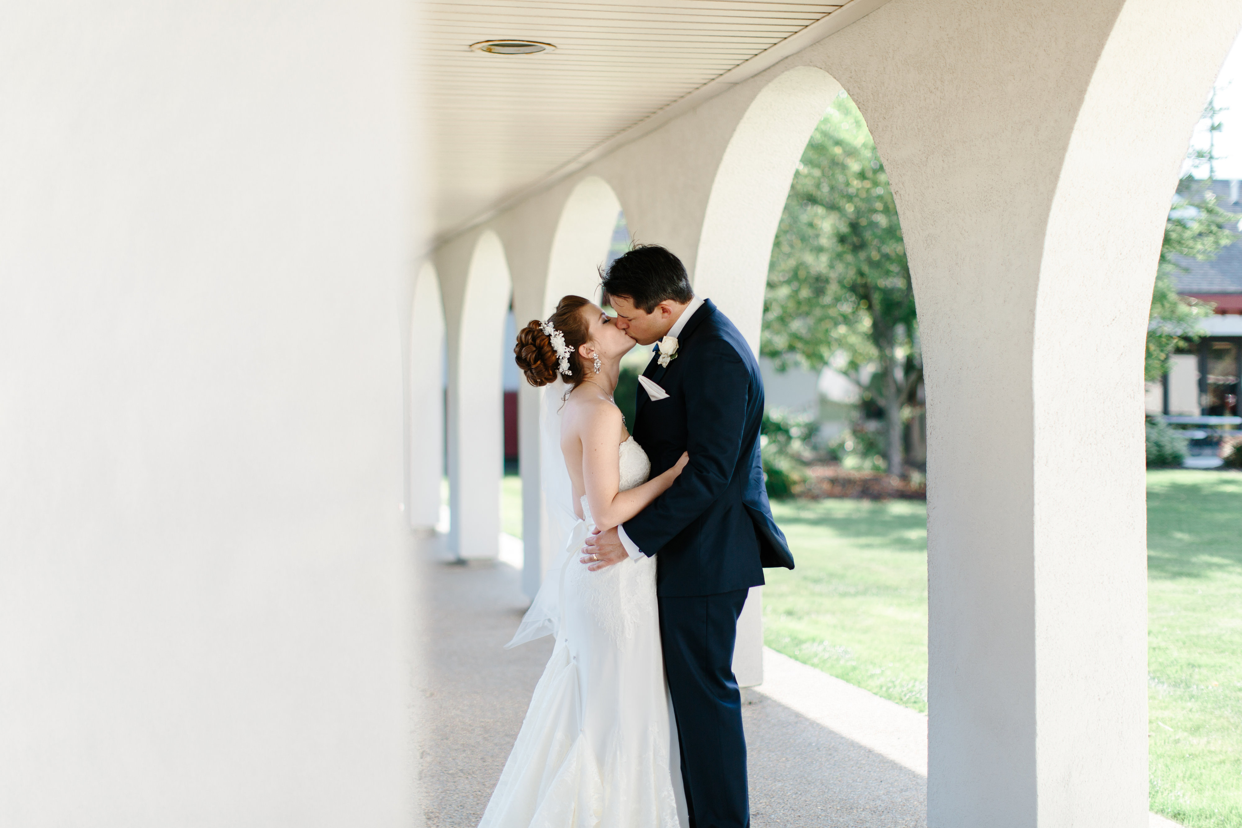 couple kiss under arch at navy and pink wedding reception