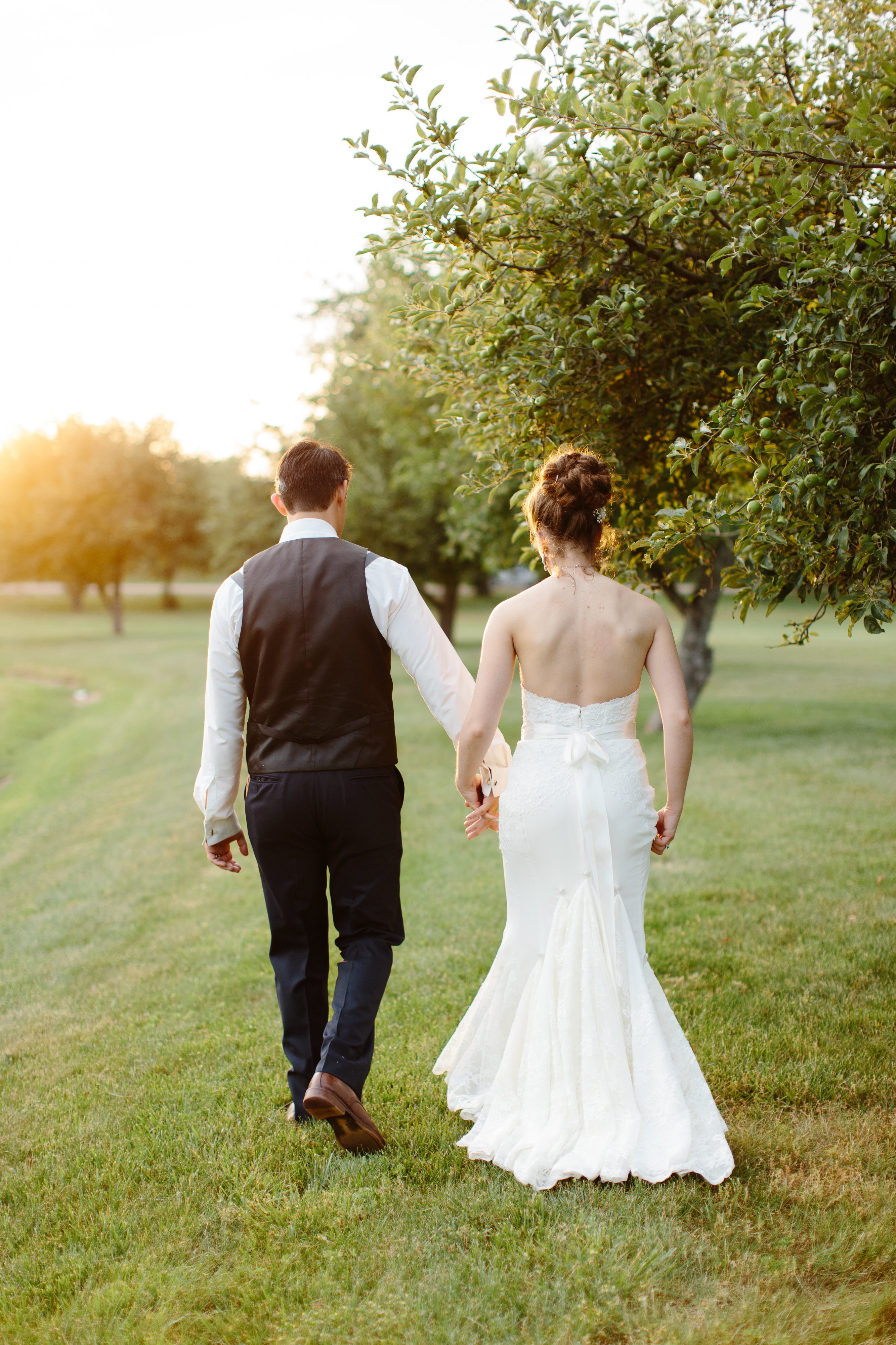 couple hold hands at sunset at their romantic wedding