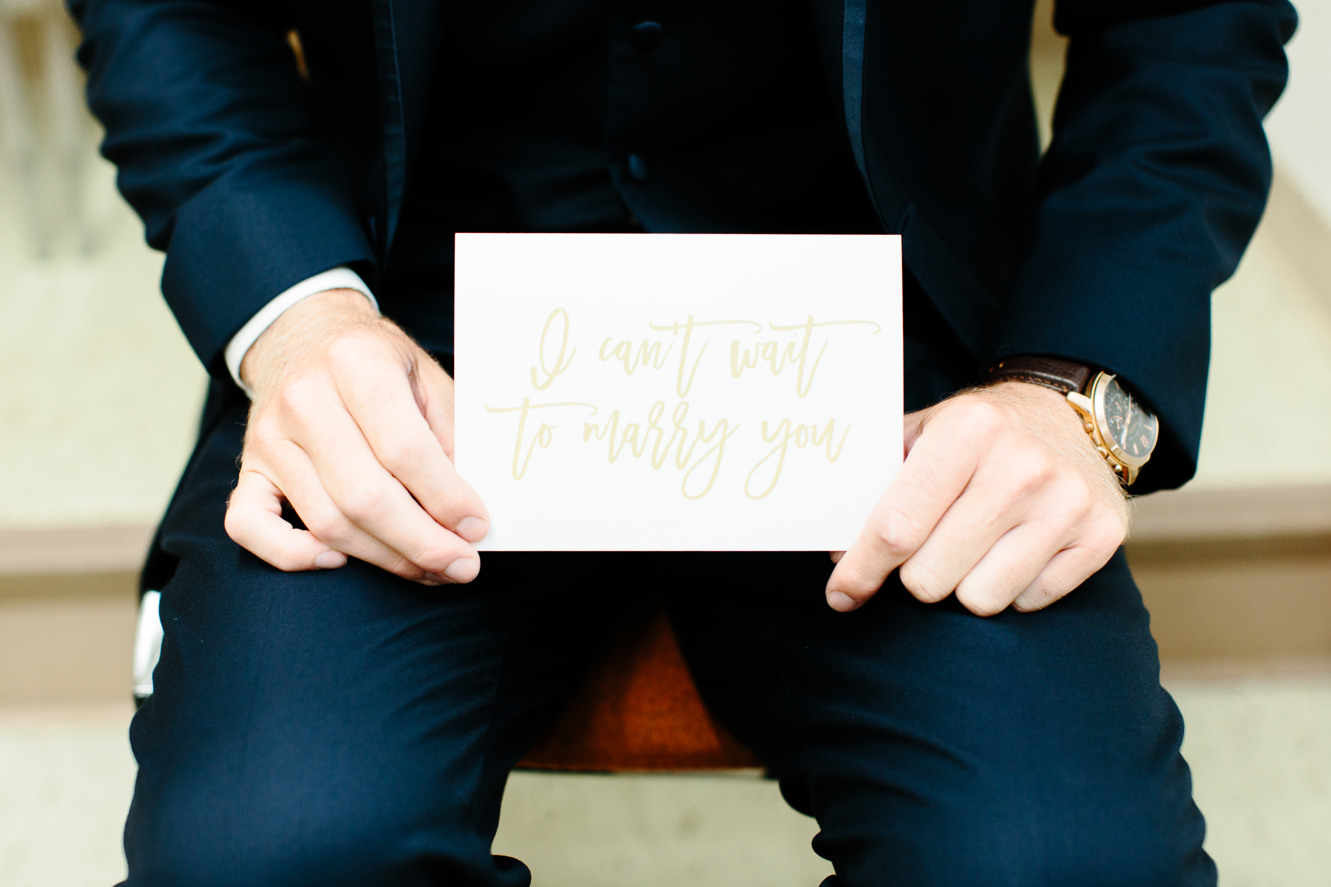 groom holds I can't wait to marry you card from bride