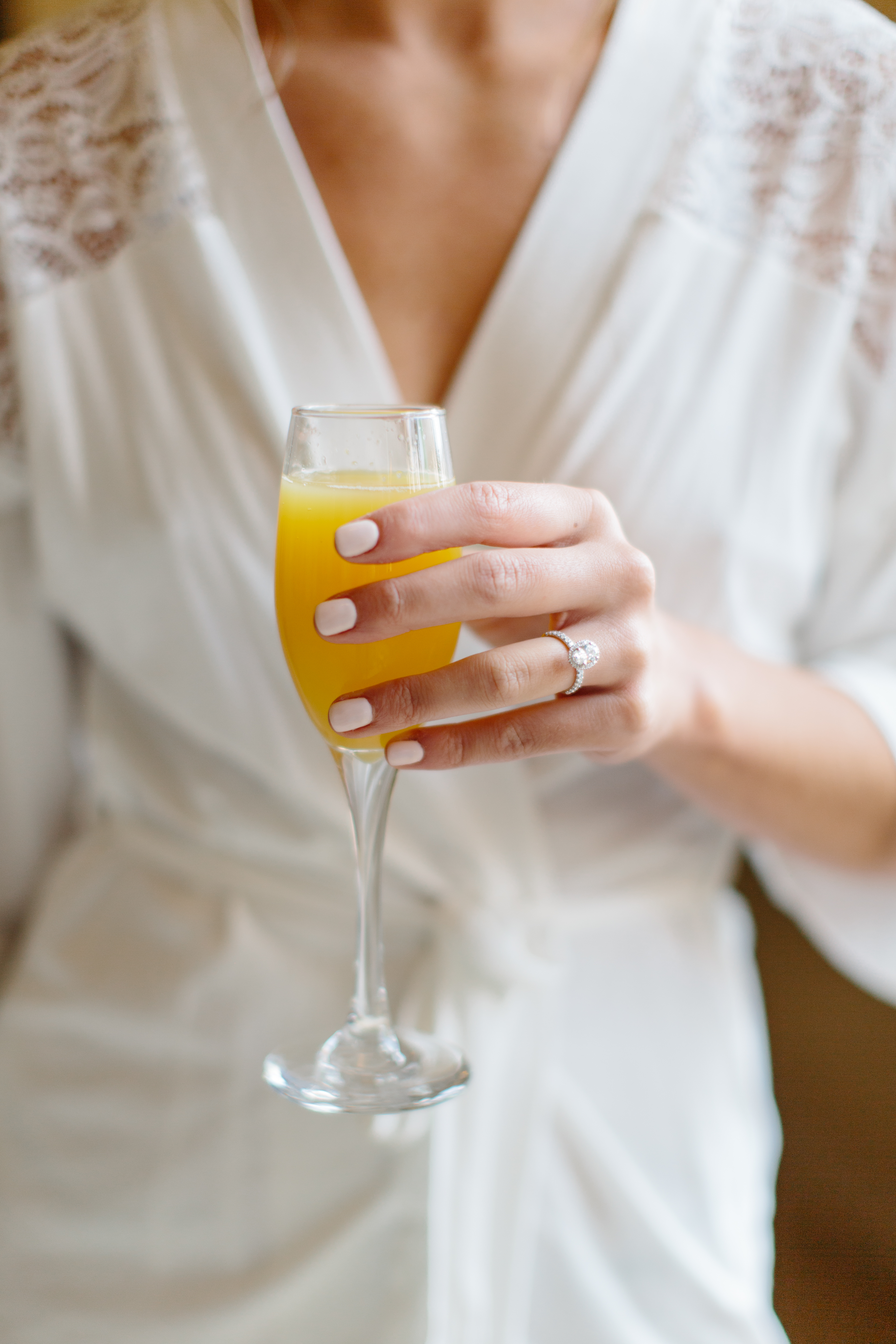 Bride holding mimosa while getting ready