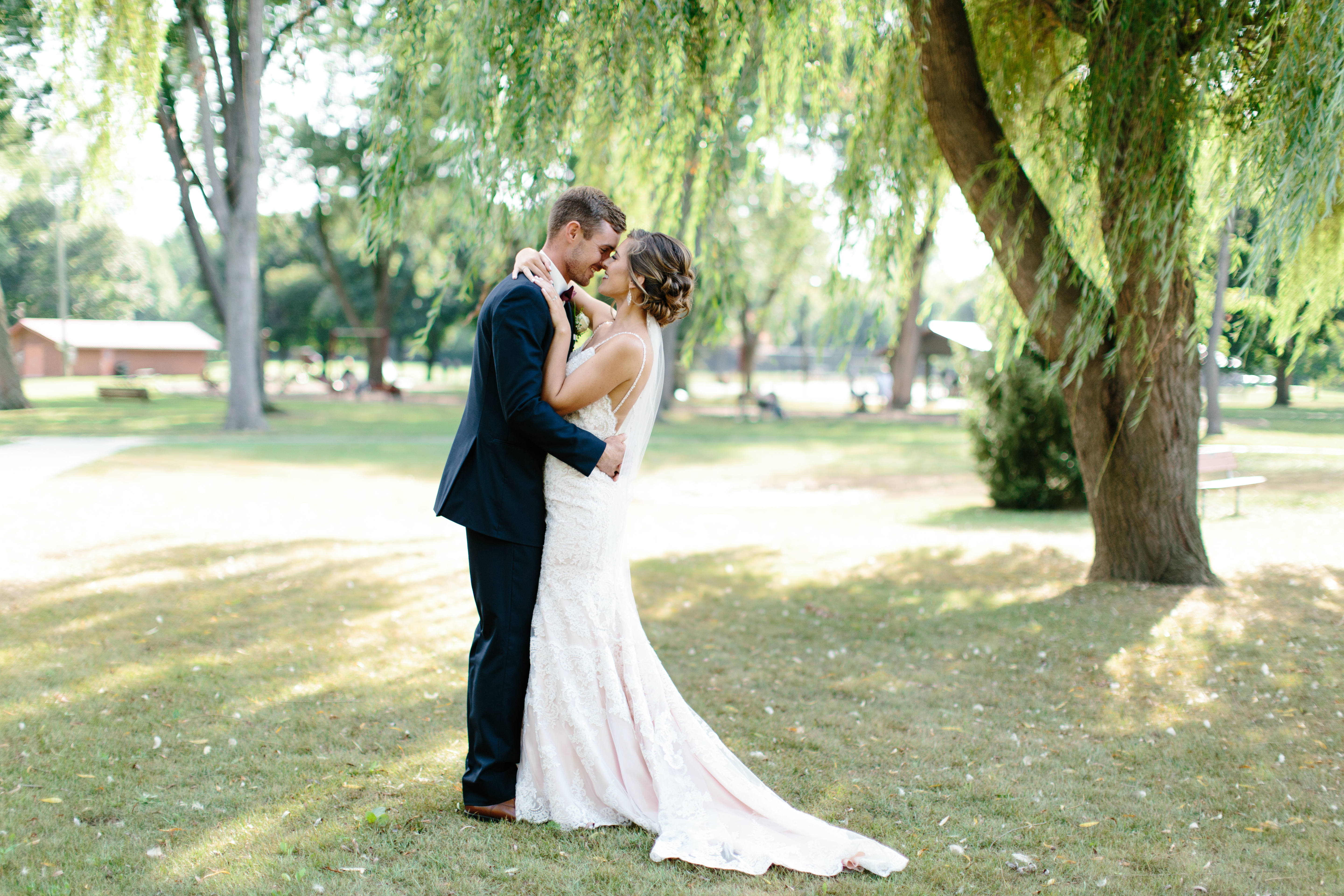 bride and groom kiss under willow tree in price park 