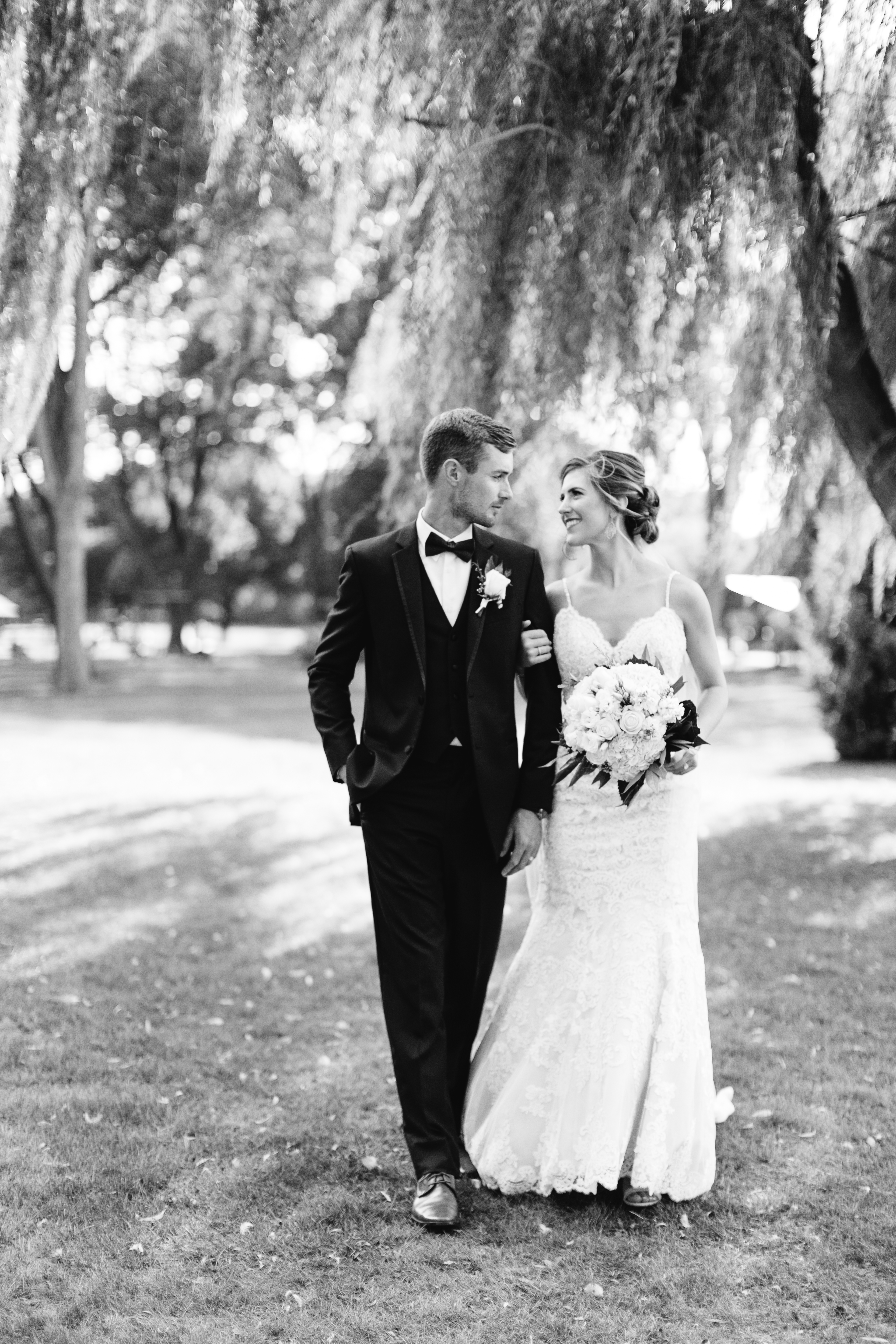 bride and groom stroll under willow tree in Price Park in North Canton