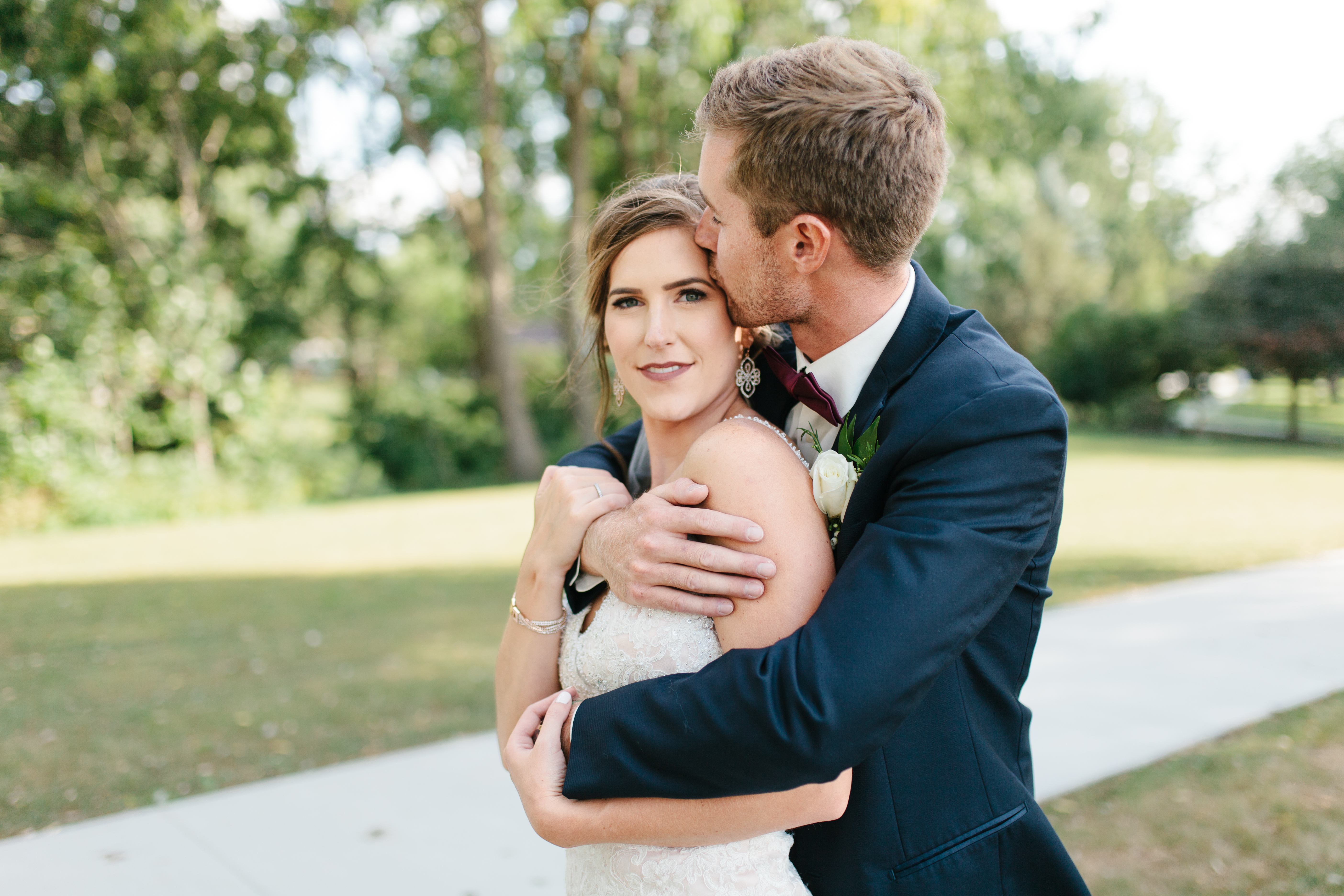 Groom hugs and kisses bride during bridal portraits