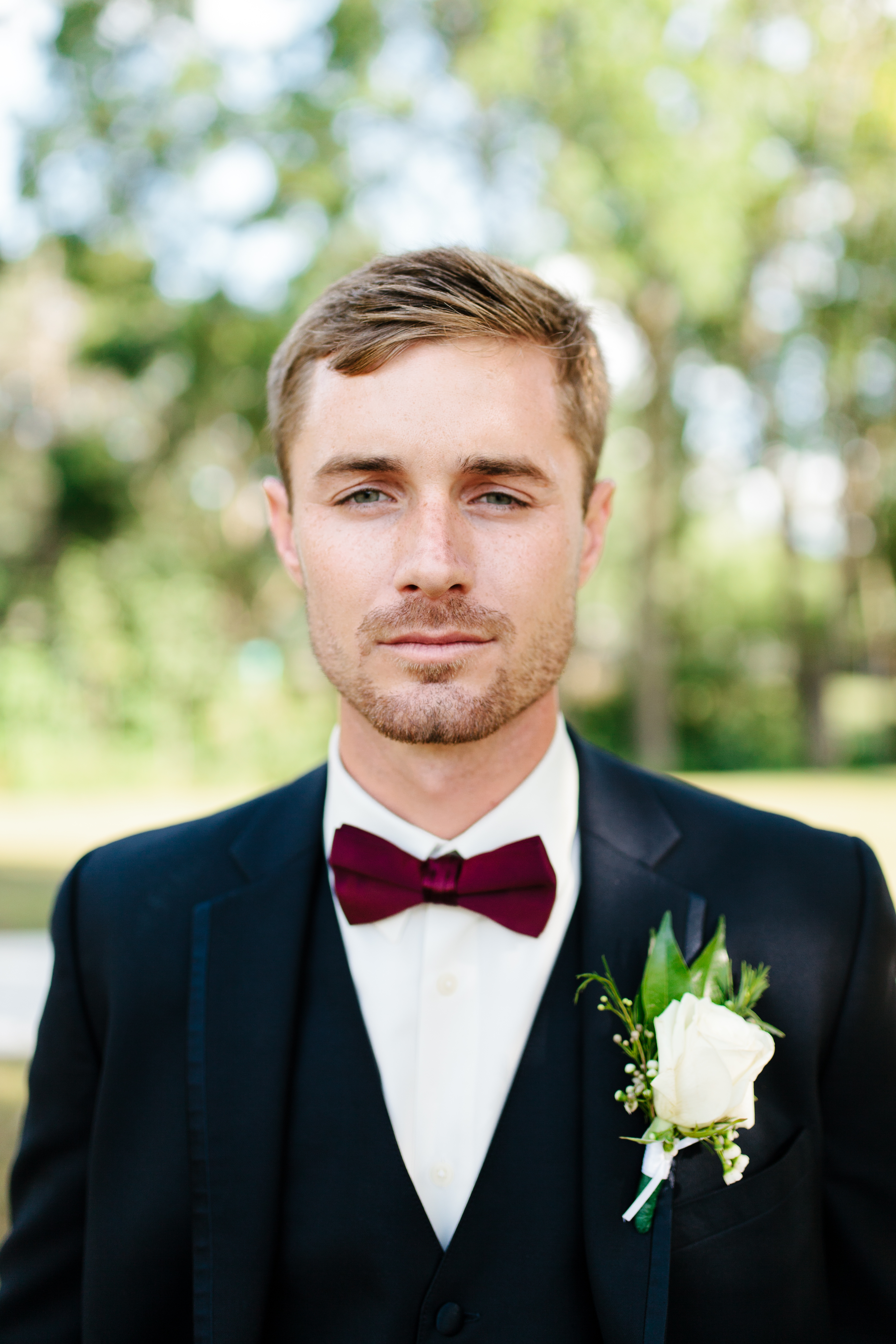 Stoic groom in navy and maroon bowtie portrait 
