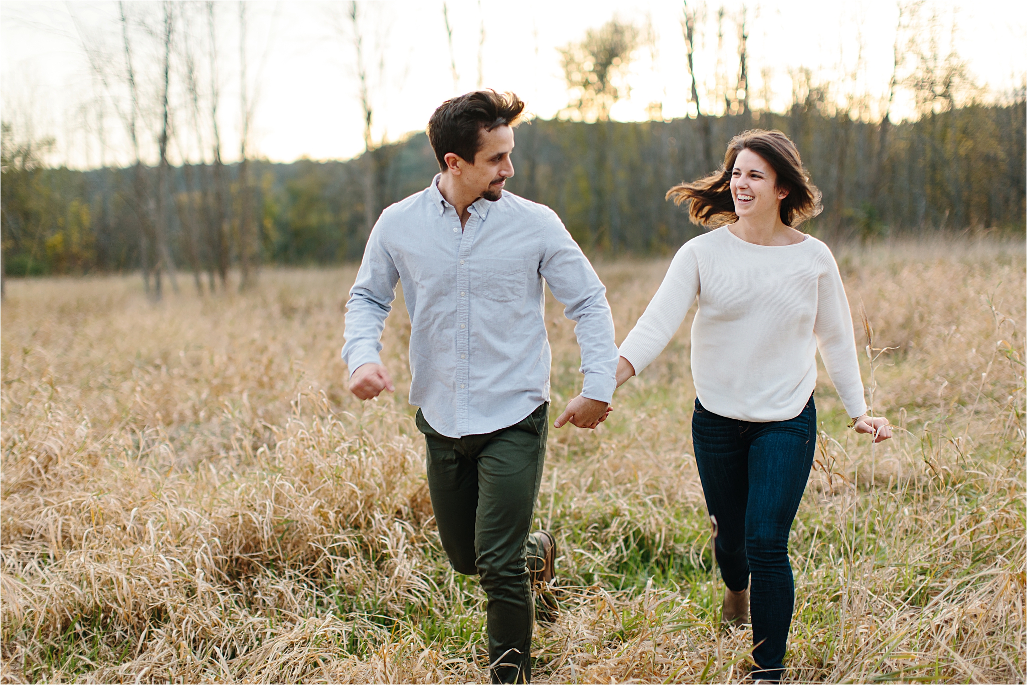 couple running through field cleveland engagement session