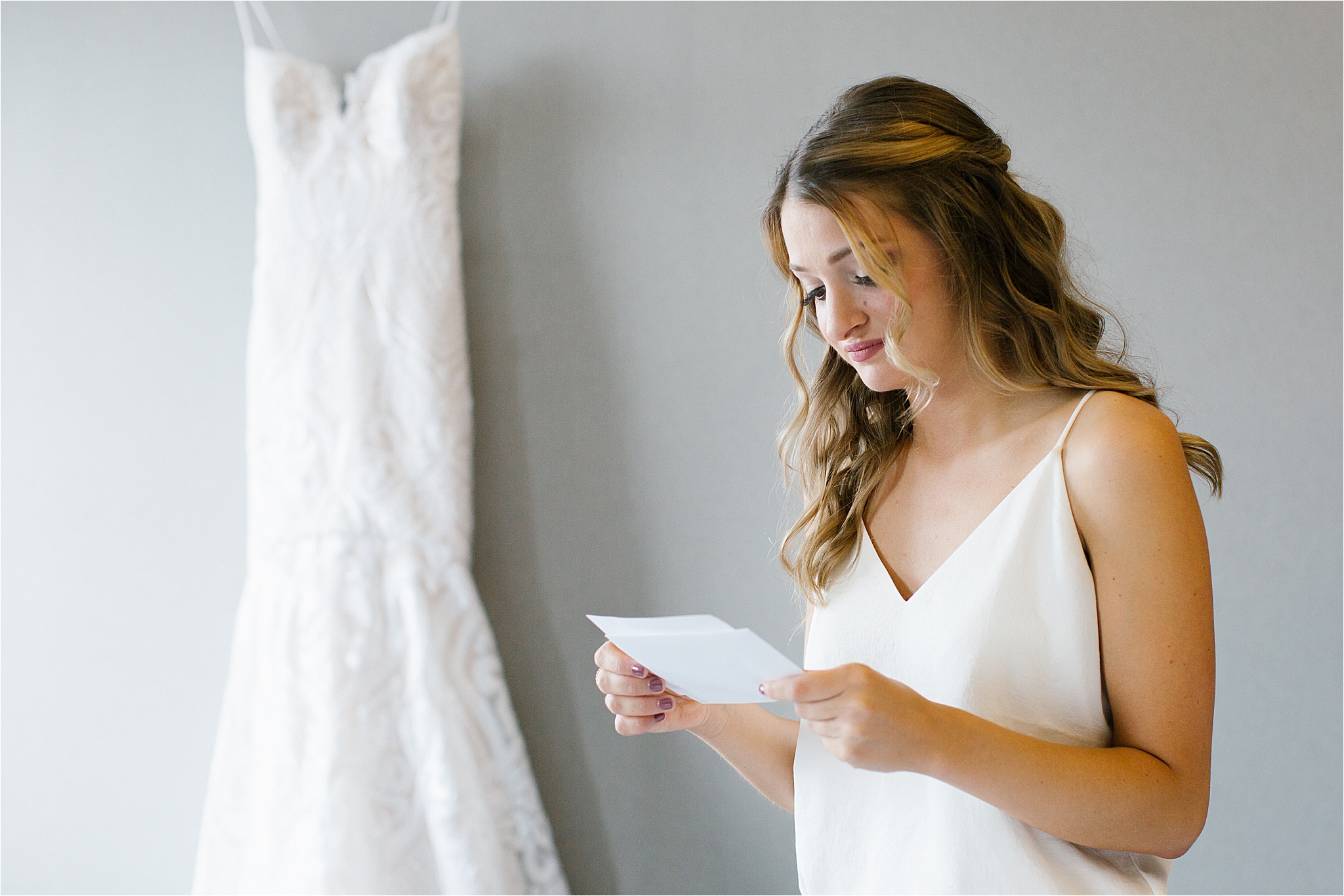 Bride reading letters in front of blush beaded Hayley Paige wedding dress