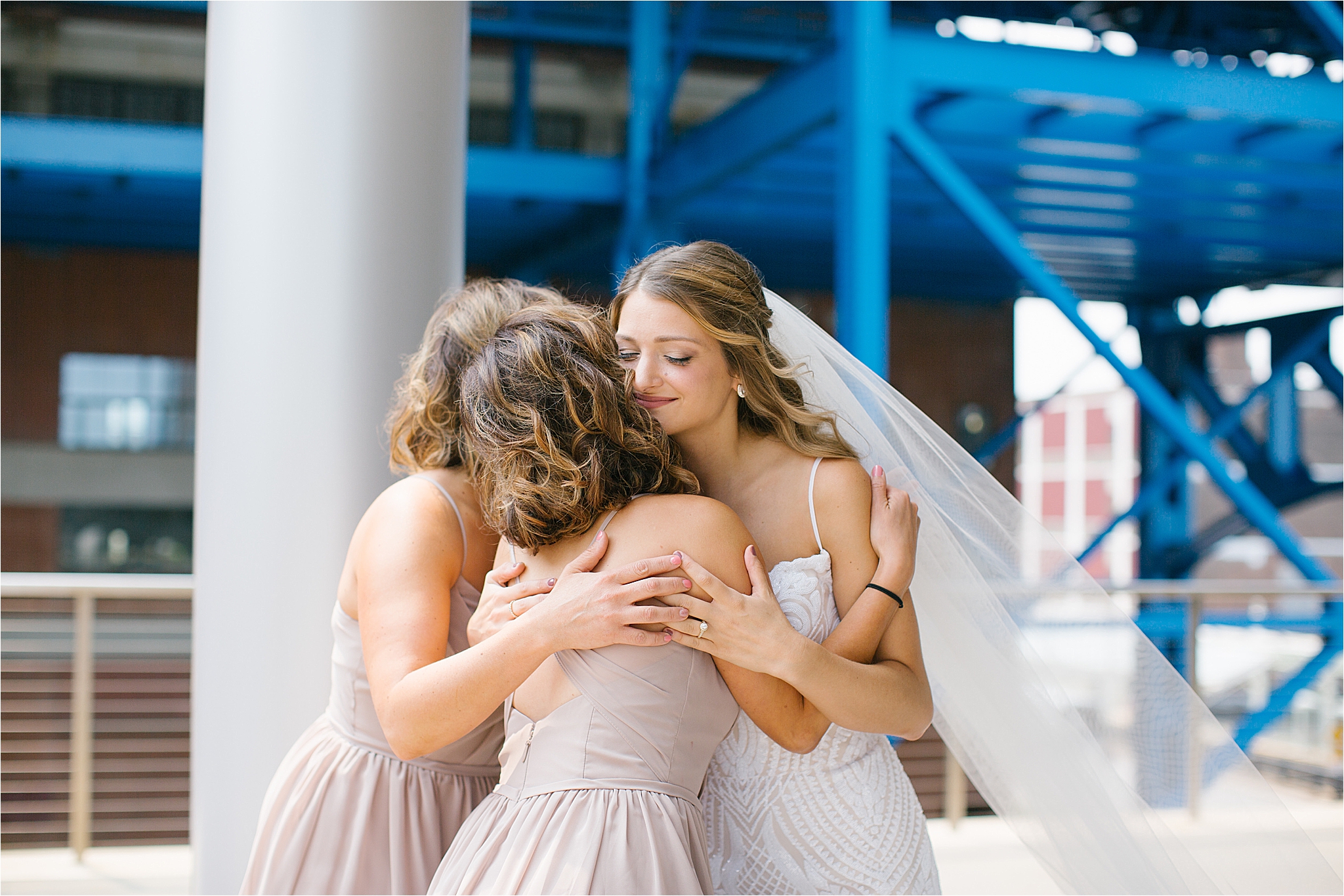 bride in blush Hayley Paige wedding dress hugging bridesmaids in mauve