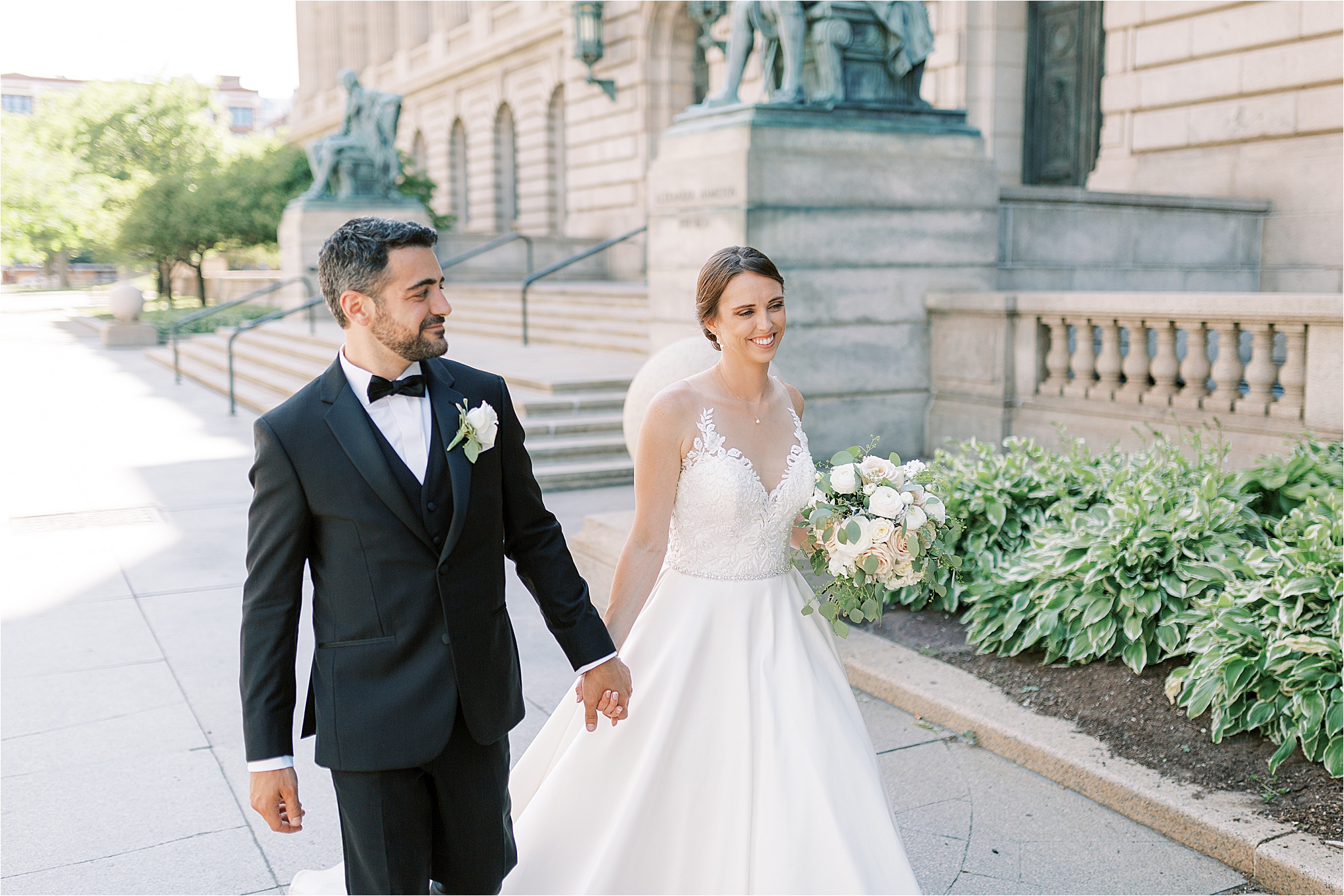 Bride and groom walking holding hands in front of Cleveland old courthouse