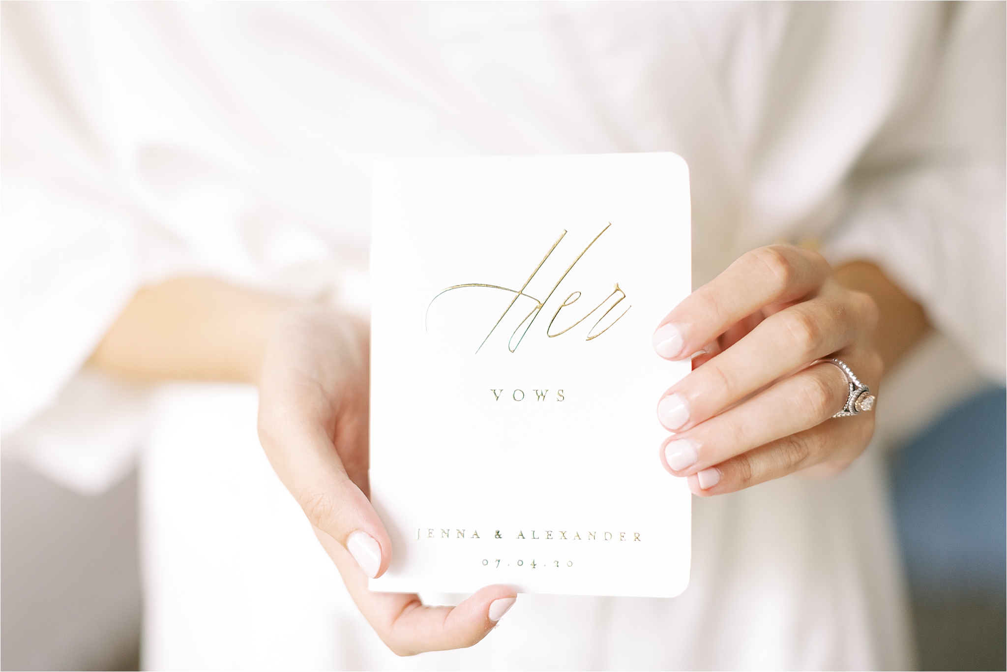white and gold vow book being held by bride