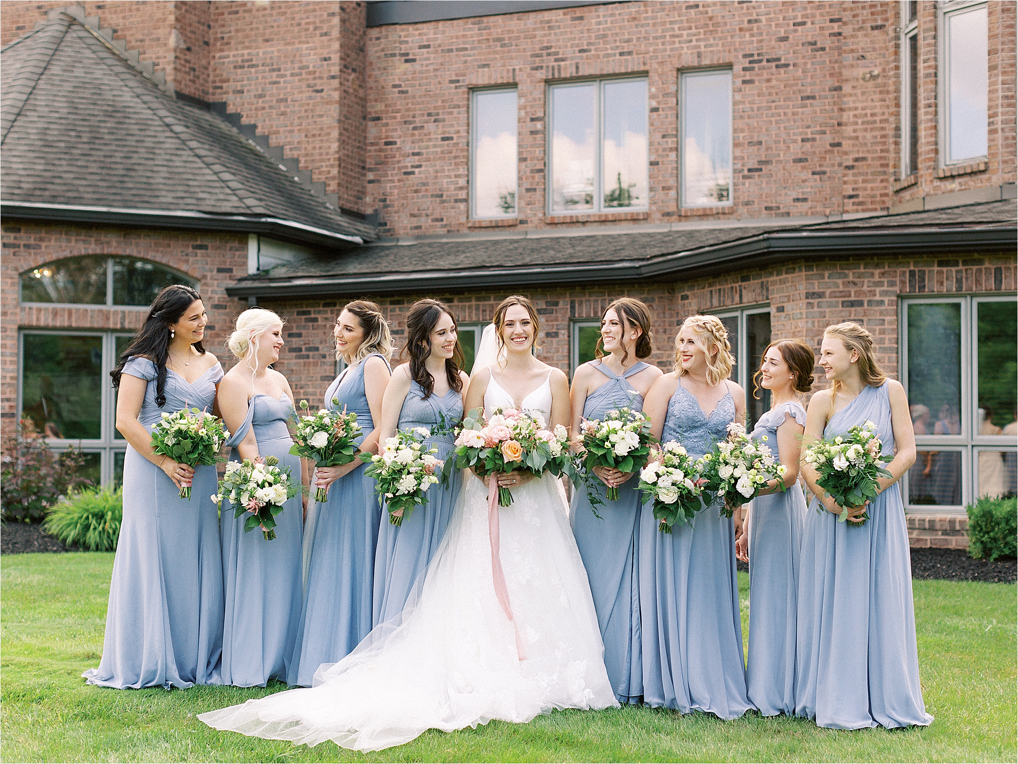  bridesmaids wearing dusty blue azazie holding colorful bouquets