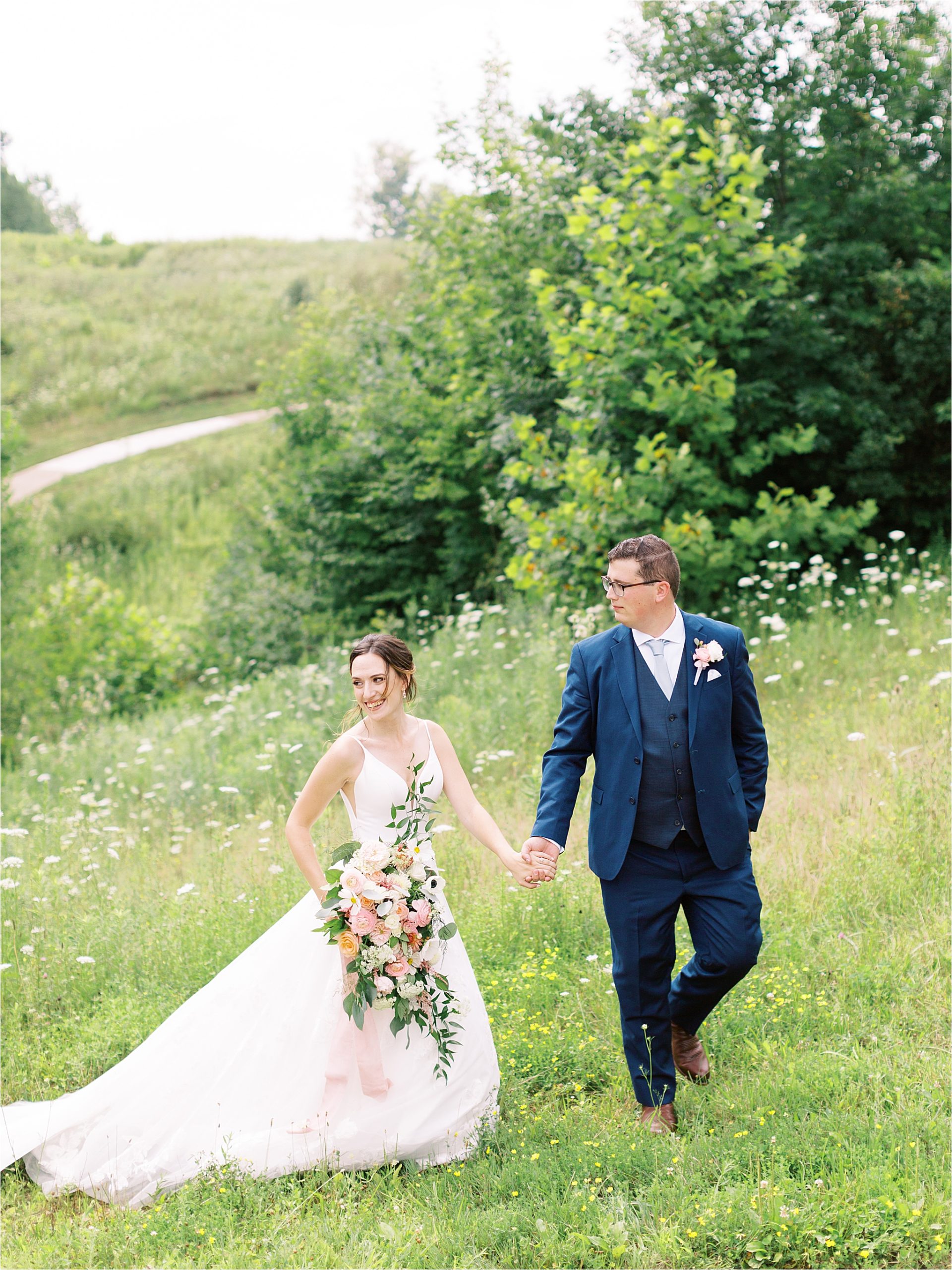 bride and groom walking together in a field at Medina wedding by cleveland wedding photographers