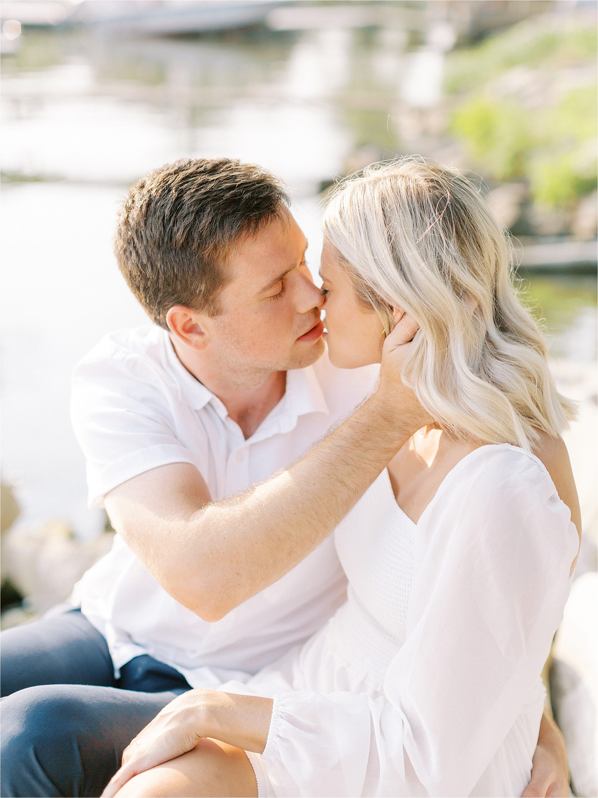 Couple kissing on rocks at lakeside engagement session