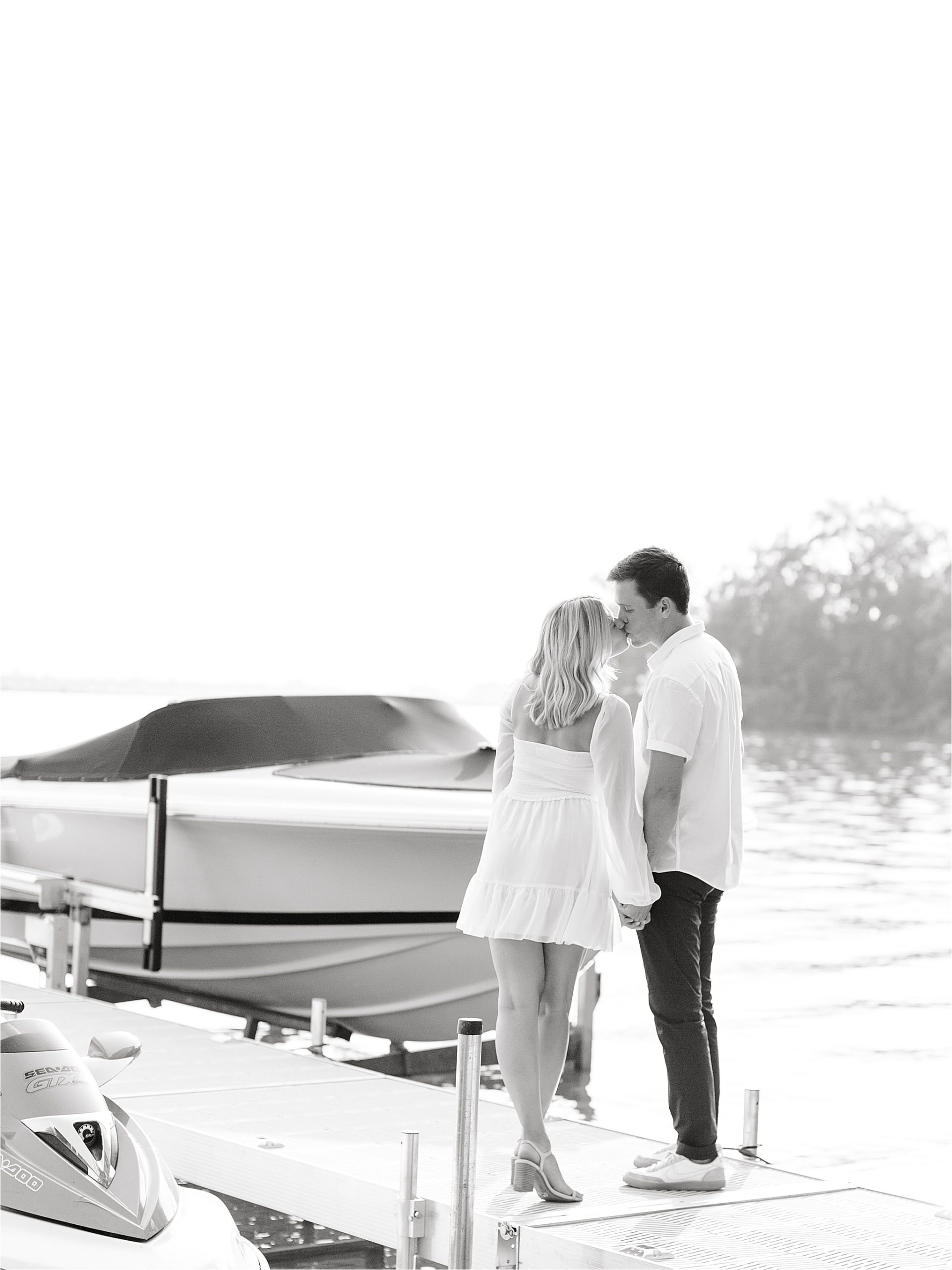 Couple kissing on rocks at lake boating engagement session