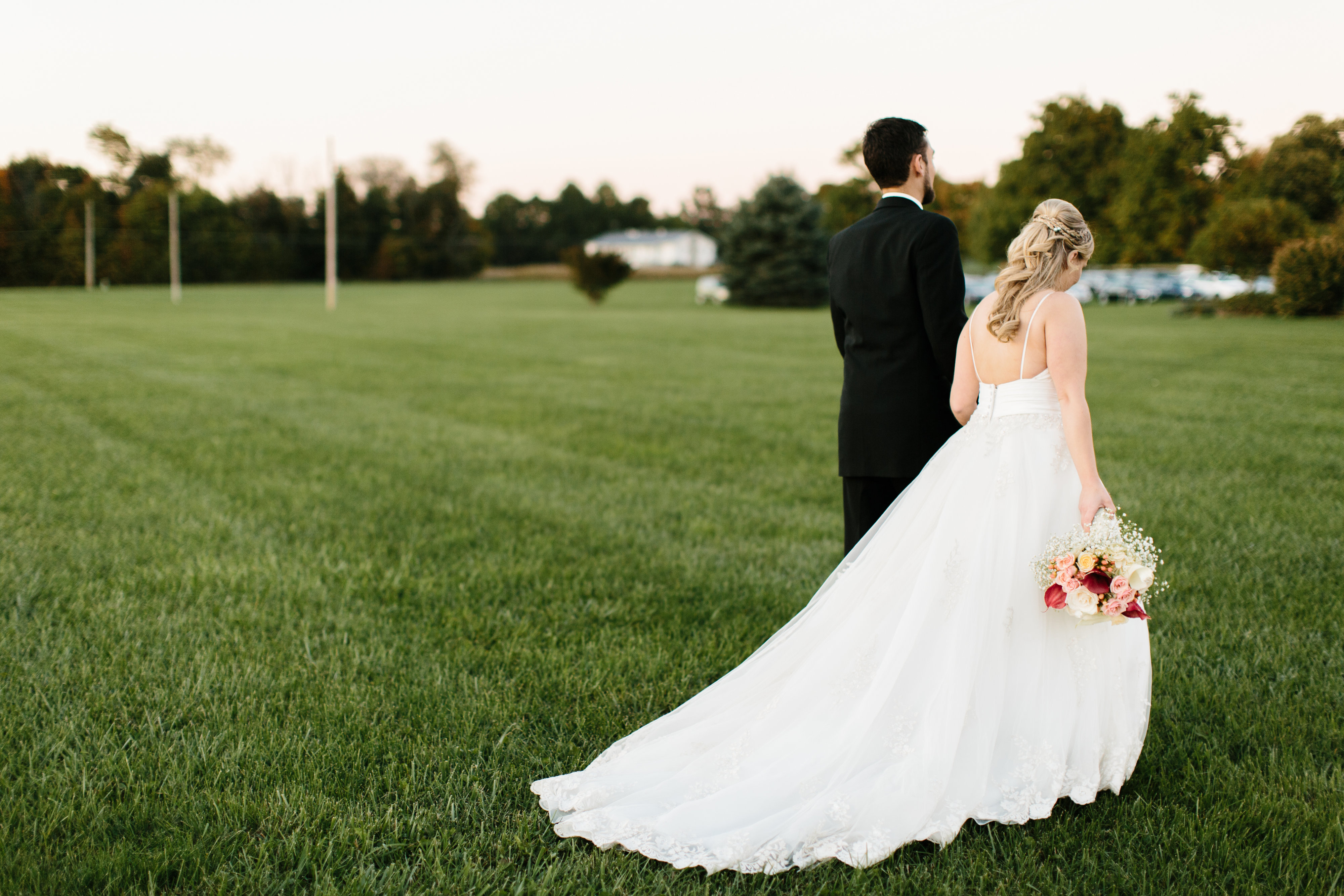 wedding couple walking holding hands  in grass 
