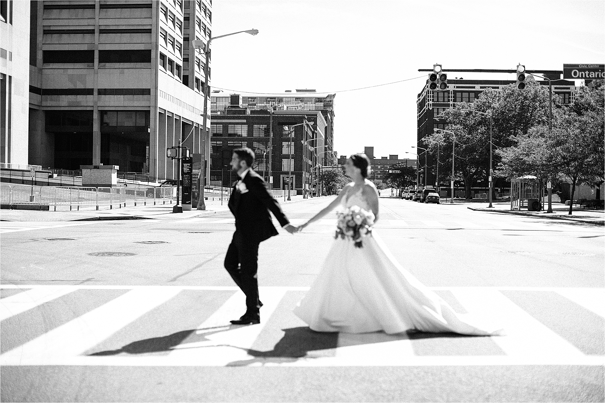 Bride and groom walking across cross walk in Cleveland